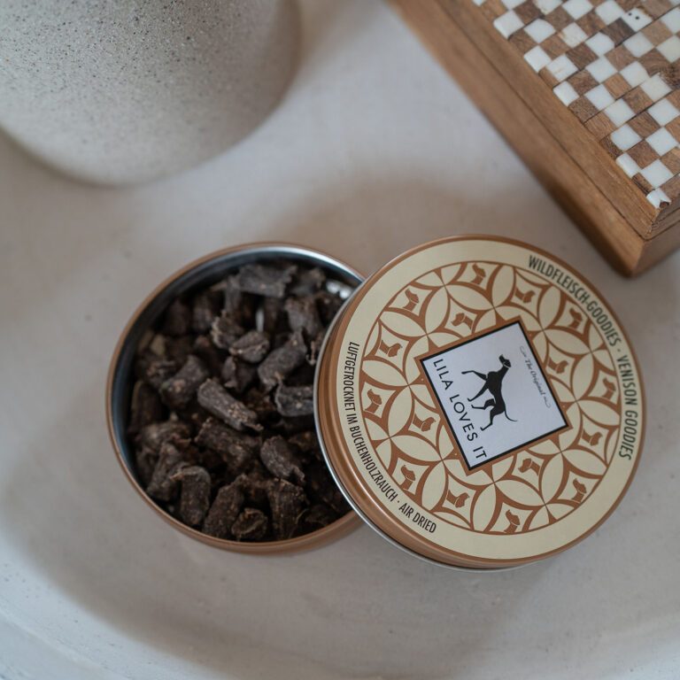 Wildfleisch-Goodies Dose im Wohnzimmerambiente (Umgeben von einer Vase und einem geschlossenen Schachbrett)