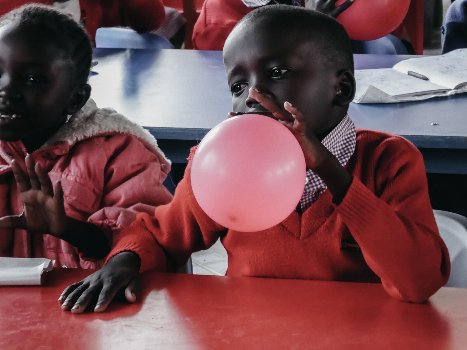 Lila loves it soziale Verantwortung in Afrika. Junge bläst Luftballon auf.