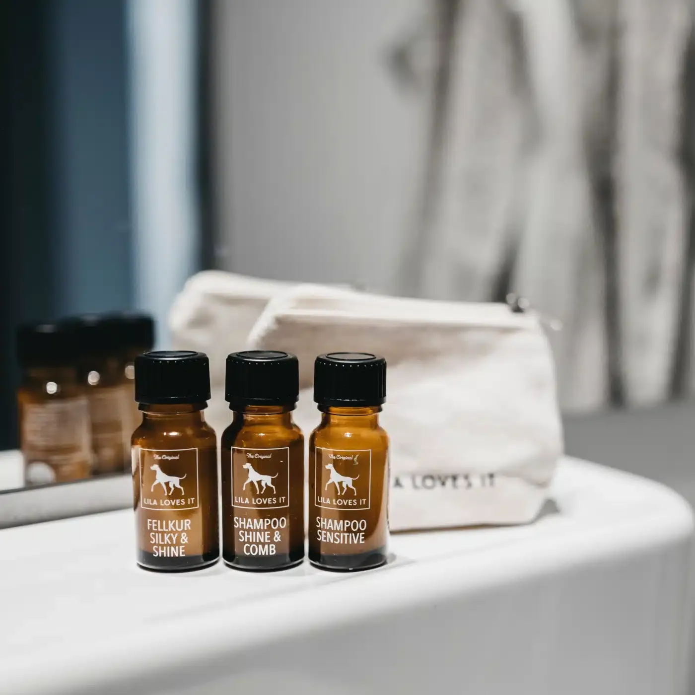 Lila loves it Pröbchenset: drei kleine Probierfläschchen Shampoo Shine and Comb, Sensitive Shampoo und Fellkur Silky and Shine. Im Hintergrund ein kleiner Jutebeutel mit Lila loves it Aufschrift