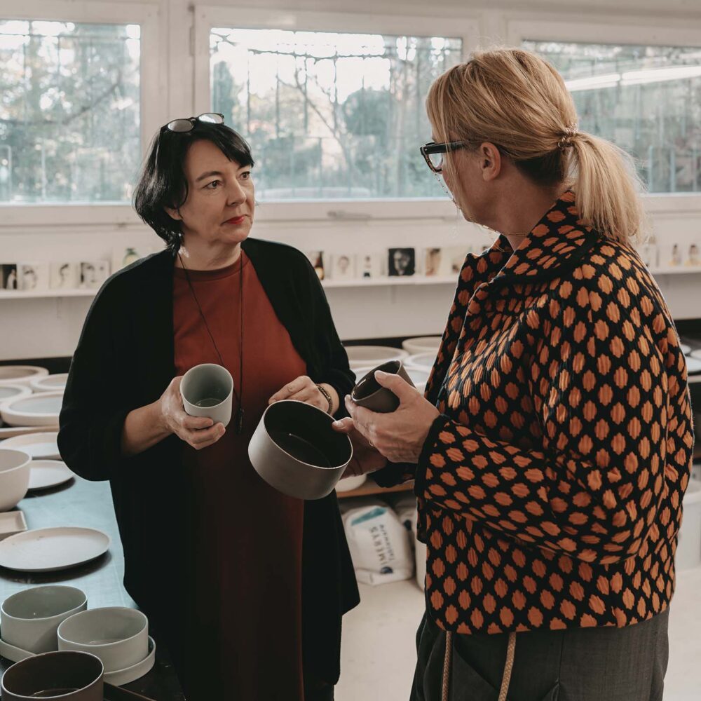 Zwei Personen unterhalten sich und halten dabei über Porzellan Näpfe und Porzellan-Becher für in den Händen